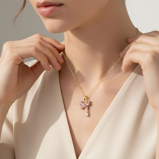 TITLIYA gold-tone butterfly pendant necklace with pink and clear crystals and a dangling teardrop charm on a model.