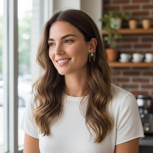 A woman wearing TITLIYA Enchanted Stud Butterfly Earrings in gold alloy with sparkling stone accents.