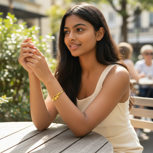 A woman wearing a TITLIYA gold-plated triple butterfly bangle while sitting at an outdoor cafe table.