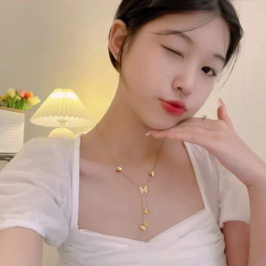 Woman wearing a delicate gold butterfly necklace by TITLIYA, featuring multiple butterfly charms on a thin chain.