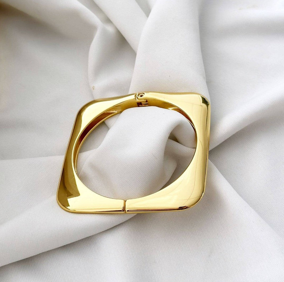 TITLIYA gold-plated square geometric bracelet with a polished finish, displayed on soft white fabric.
