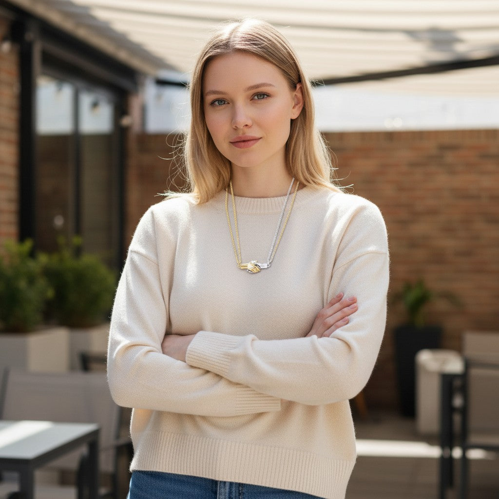 Woman wearing a TITLIYA magnet handshake couple necklace with gold and silver chains, styled with a beige sweater.