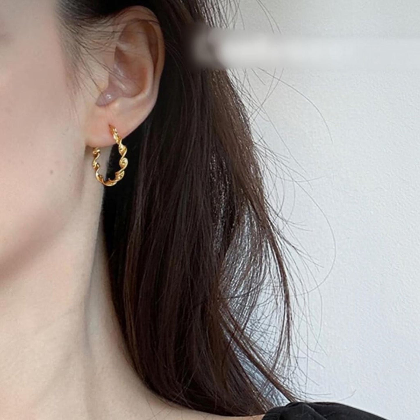 TITLIYA medium gold twisted hoop earring worn on a woman's ear for an elegant daily look.
