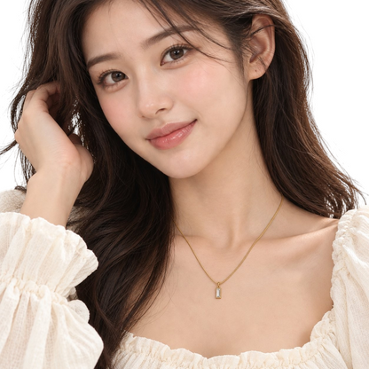 A woman wearing a TITLIYA Korean style gold mini rectangle pendant necklace with a clear stone on a fine gold chain.