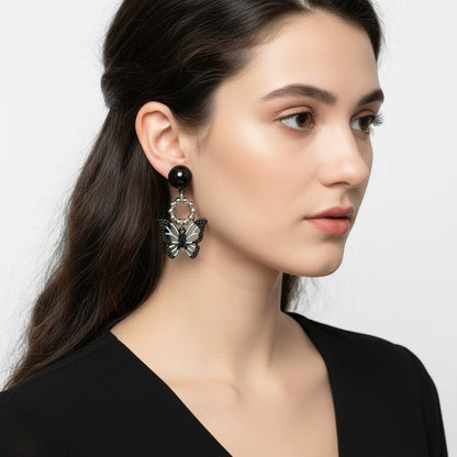 Model wearing TITLIYA Korean-style acrylic butterfly earrings with black and light blue details on a white background.
