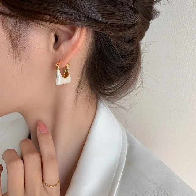 TITLIYA gold-tone hoop earrings featuring a unique white handbag-shaped charm worn by a woman.