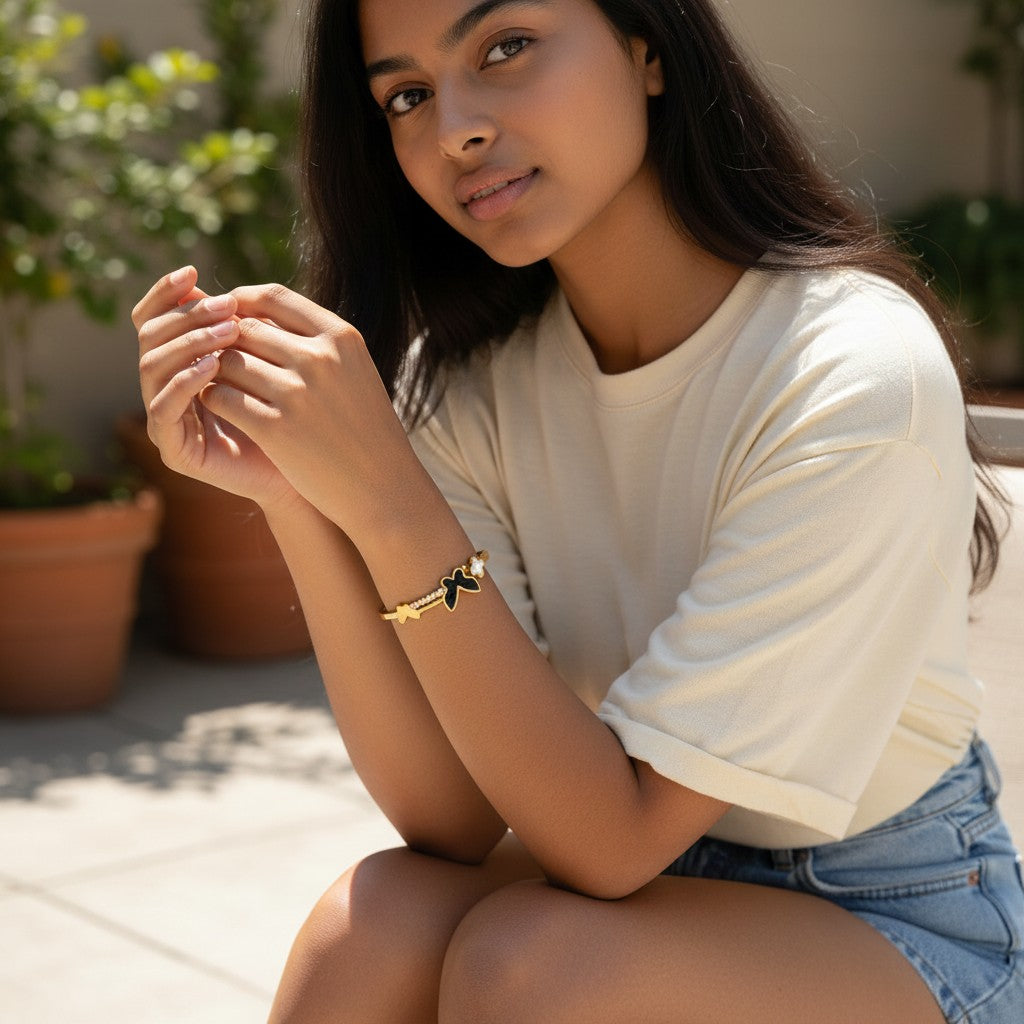 TITLIYA gold-tone hinged bangle featuring a black butterfly, white floral accent, and crystals on a model.