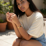 TITLIYA gold-tone hinged bangle featuring a black butterfly, white floral accent, and crystals on a model.