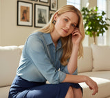 Blonde woman wearing small black flower earrings by TITLIYA, styled with a denim shirt for an elegant everyday look.