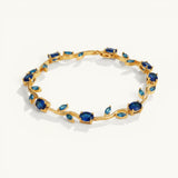 TITLIYA Blue Tulip Bracelet featuring a gold-tone vine design with oval-cut deep blue stones on a white background.