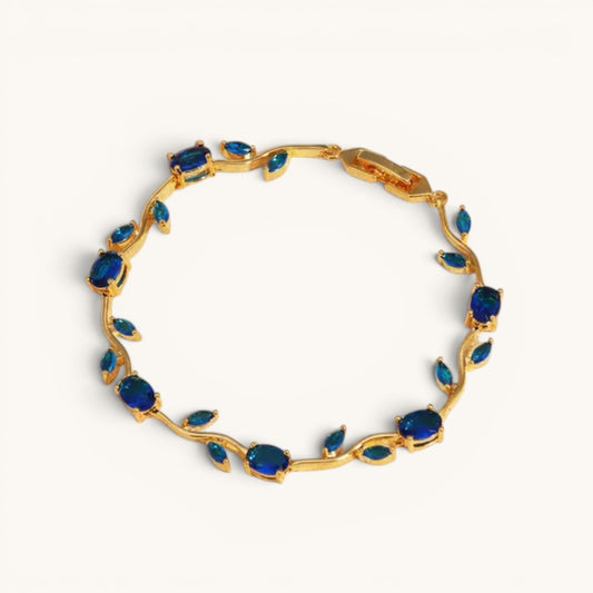 TITLIYA gold-tone vine bracelet featuring deep blue oval-cut stones in a nature-inspired floral design.