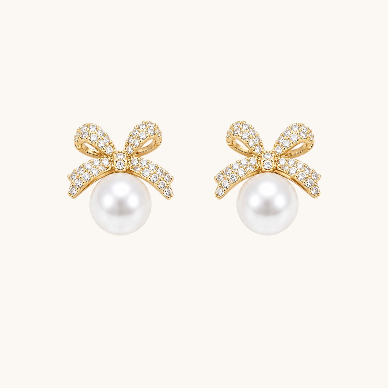 TITLIYA gold-toned bow stud earrings featuring sparkling cubic zirconia stones and a lustrous white pearl drop.