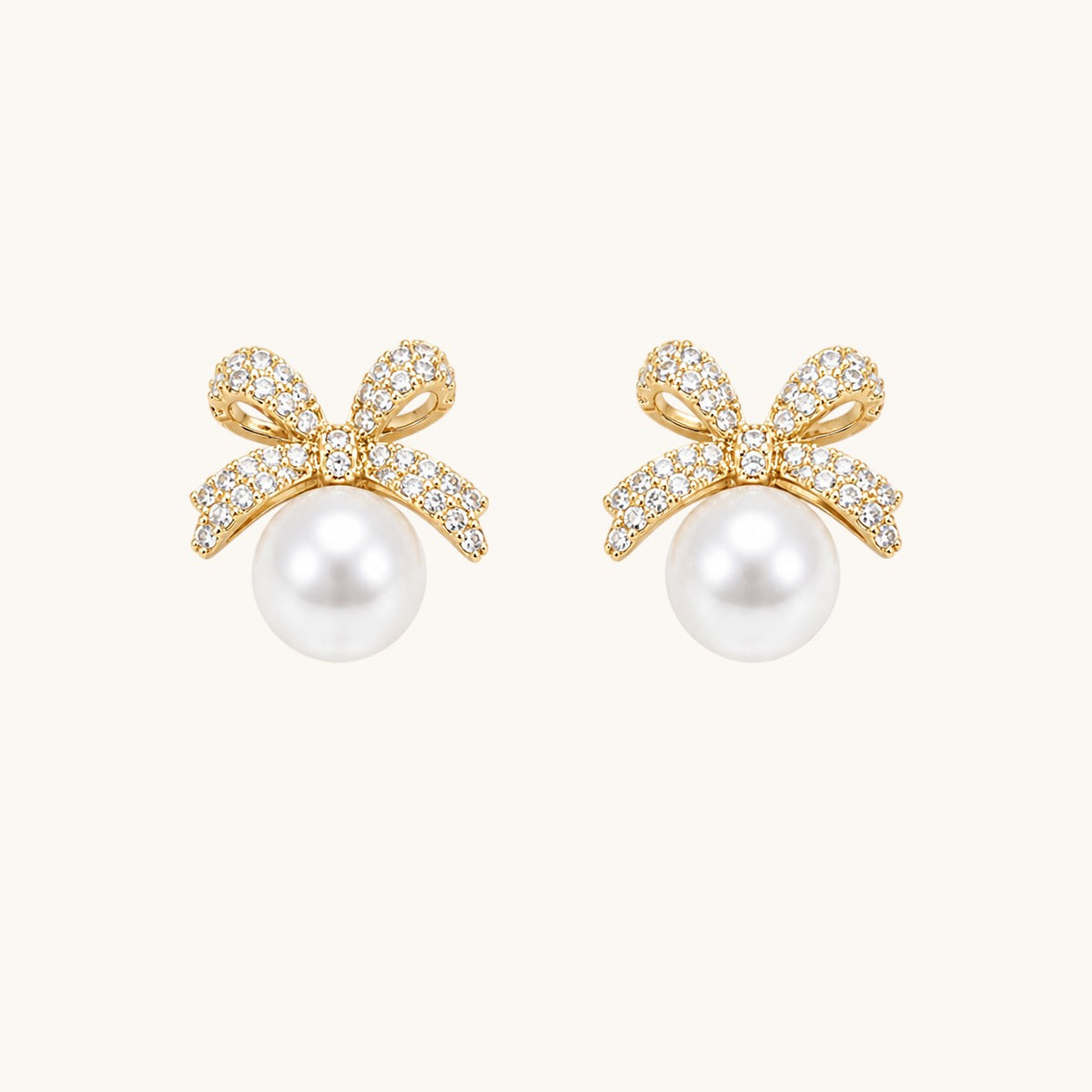 TITLIYA gold-toned bow stud earrings featuring sparkling cubic zirconia stones and a lustrous white pearl drop.