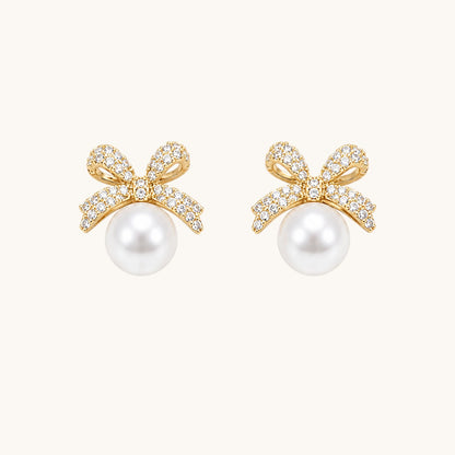 TITLIYA gold-toned bow stud earrings featuring sparkling cubic zirconia stones and a lustrous white pearl drop.