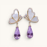 TITLIYA Korean-style butterfly earrings with white mother-of-pearl, gold trim, and dangling purple crystal teardrops.