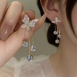 TITLIYA gold-tone butterfly dangle earrings with sparkling crystal accents, worn by a woman for a festive look.