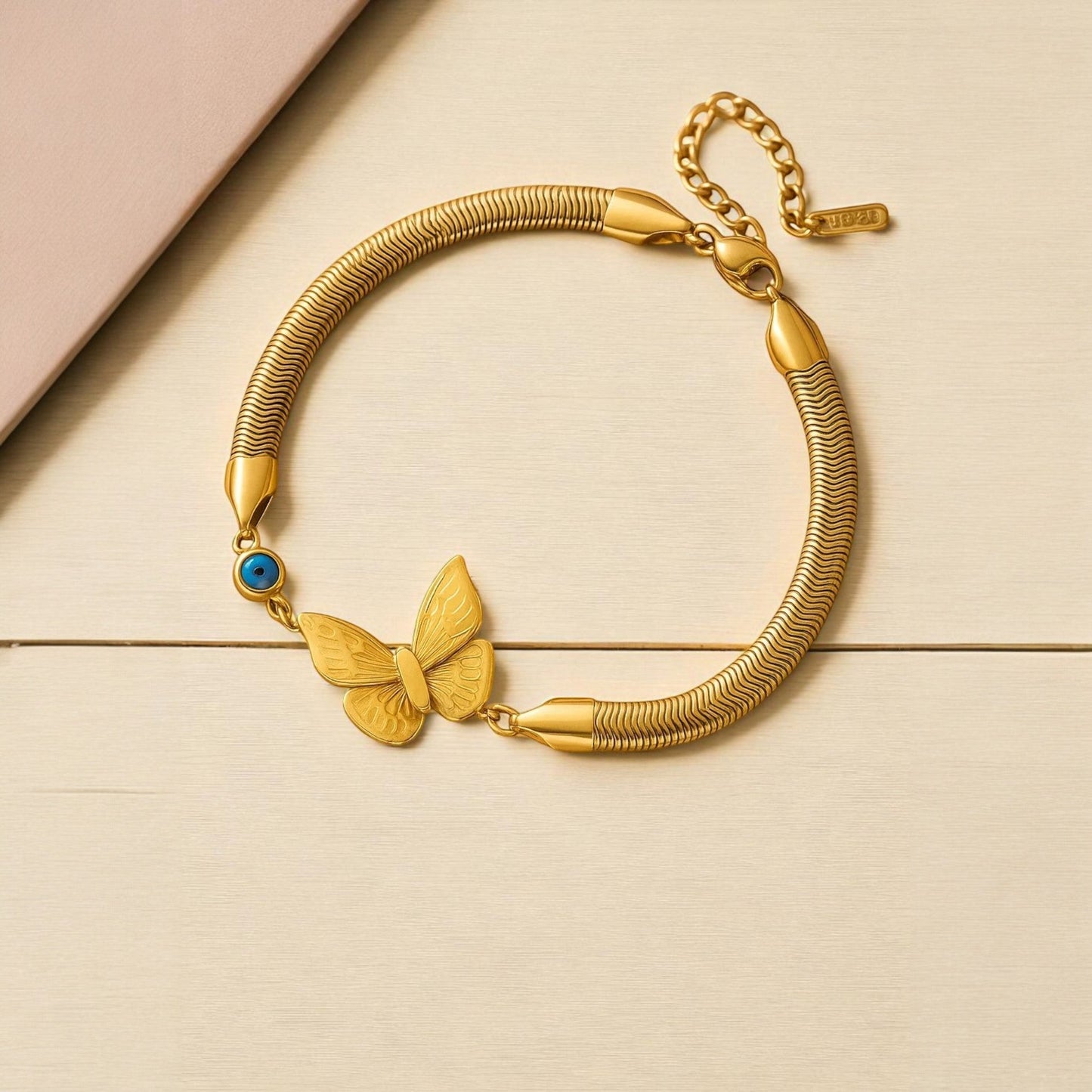 TITLIYA gold-tone snake chain bracelet featuring a butterfly charm and a blue evil eye bead in a boho style.