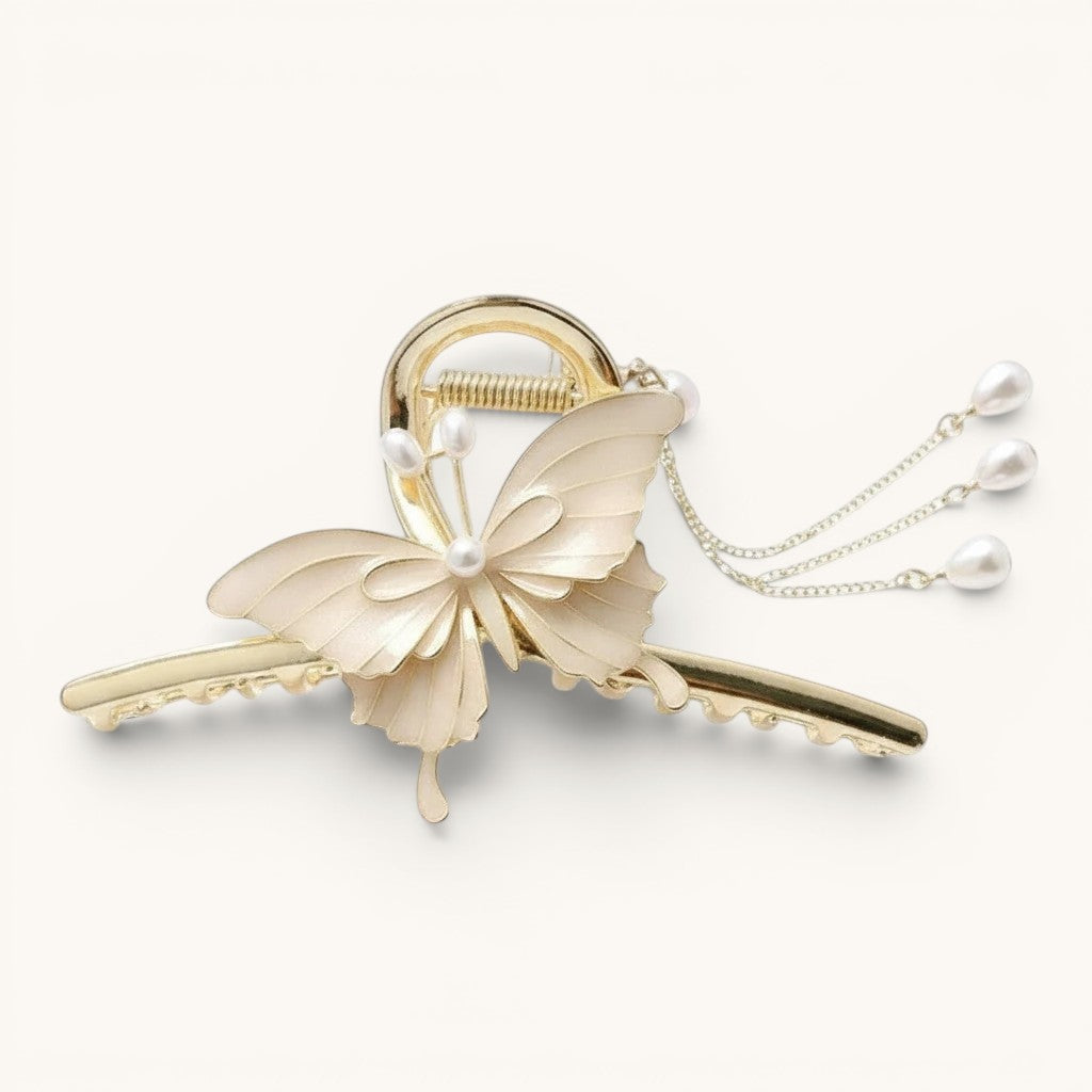 TITLIYA off-white enamel butterfly hair claw clip with gold-tone metal base and dangling faux pearl chain accents.