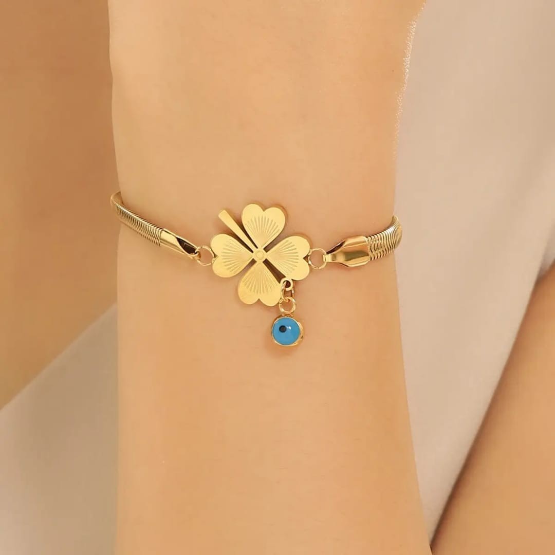 TITLIYA gold-tone snake chain bracelet featuring a heart-leaf clover charm and a small blue evil eye pendant.