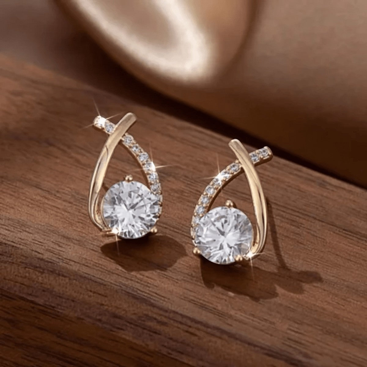 TITLIYA gold-tone crystal cross-shaped earrings with sparkling round stones on a wooden surface.