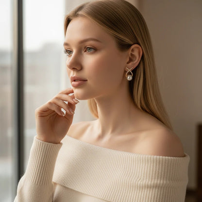 Model wearing elegant TITLIYA diamond studded cross earrings with a dangling pearl, perfect for special occasions.