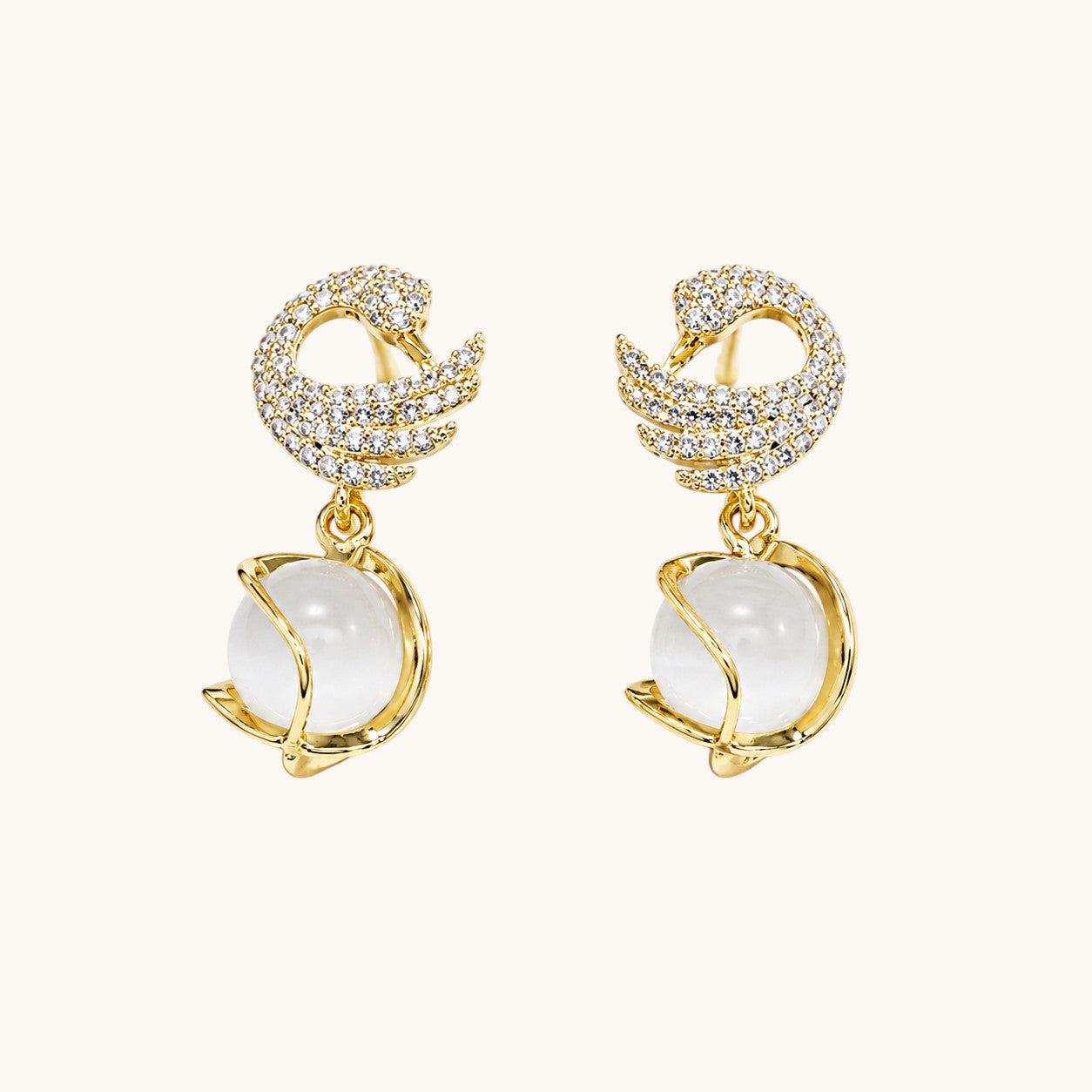 TITLIYA gold-plated dove shape earrings featuring crystal pavé wings and a dangling white moonstone sphere.