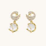 TITLIYA gold-plated dove shape earrings featuring crystal pavé wings and a dangling white moonstone sphere.