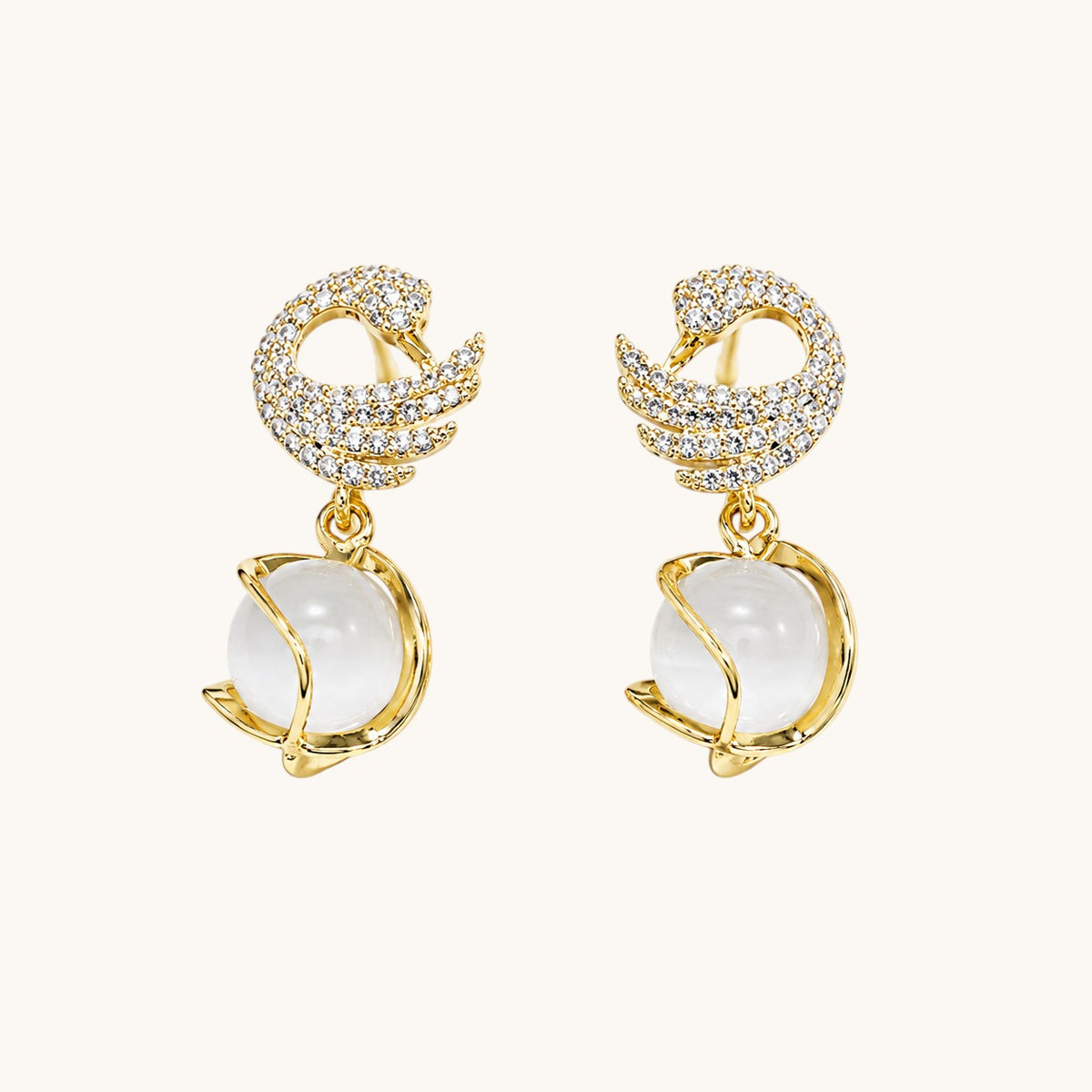 TITLIYA gold-plated dove shape earrings featuring crystal pavé wings and a dangling white moonstone sphere.
