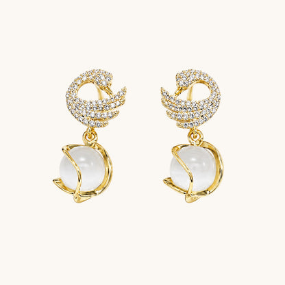 TITLIYA gold-plated dove shape earrings featuring crystal pavé wings and a dangling white moonstone sphere.