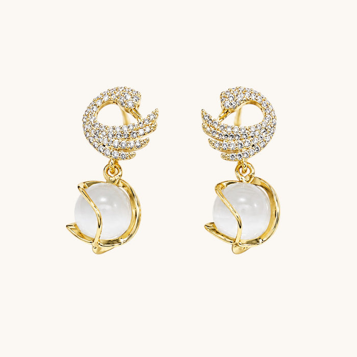 TITLIYA gold-plated dove shape earrings featuring crystal pavé wings and a dangling white moonstone sphere.