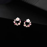 TITLIYA mini flower and butterfly stud earrings with pink crystals and white floral accents on a black background.