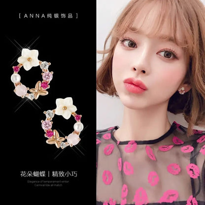 TITLIYA mini flower and butterfly hoop earrings with pink crystals, pearls, and white floral accents on a model.