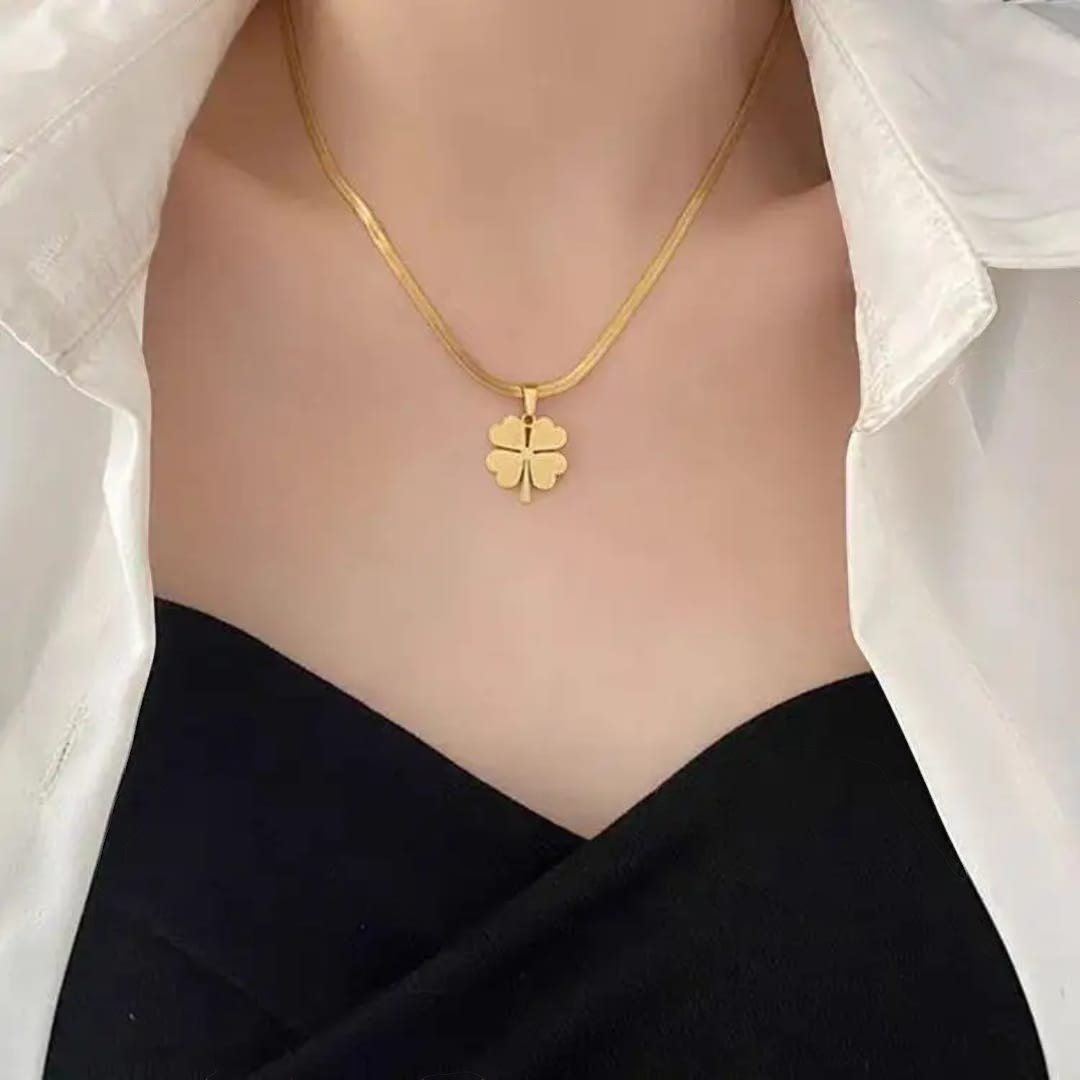 TITLIYA gold-toned flower clover pendant necklace on a sleek chain worn with a white shirt and black top.