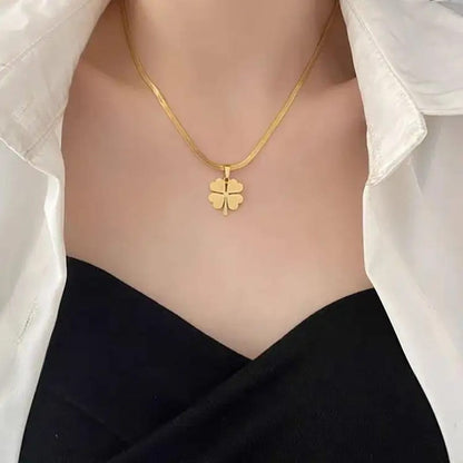 TITLIYA gold-toned flower clover pendant necklace on a sleek chain worn with a white shirt and black top.