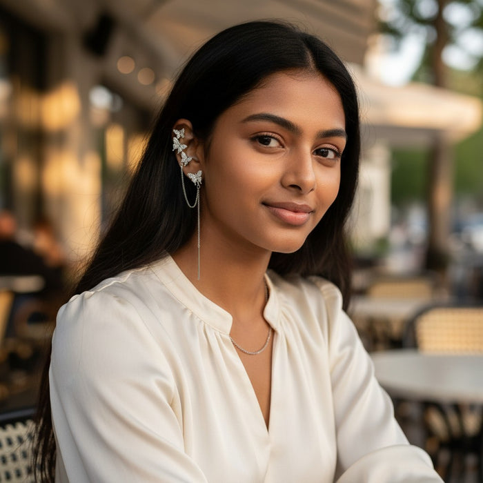 TITLIYA gold butterfly ear climber with delicate chain detail worn by a woman in a cream blouse outdoors.