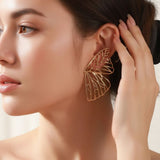 Model wearing TITLIYA gold plated butterfly wing hoop earrings with intricate cut-out detailing for a premium look.