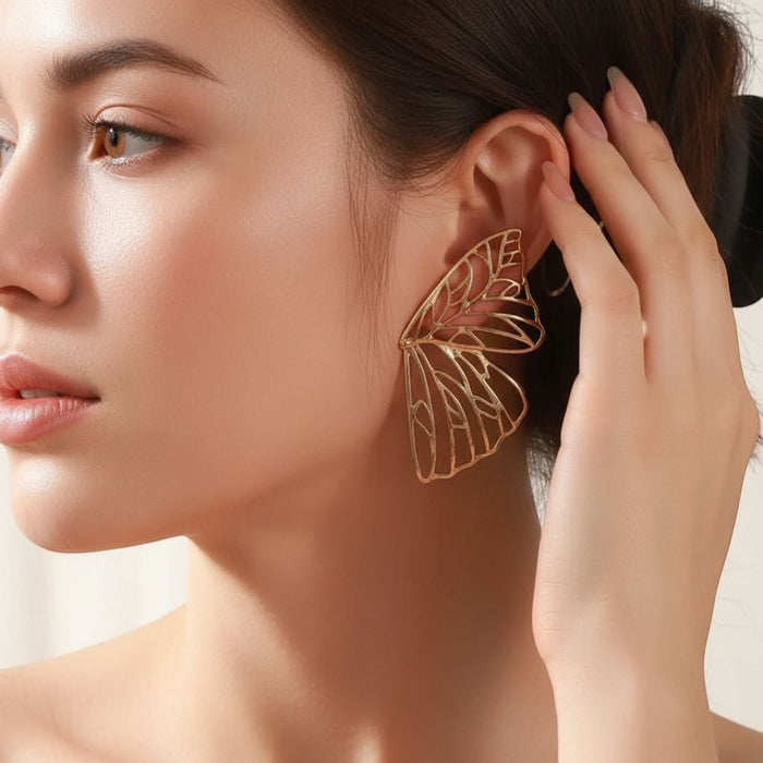Model wearing TITLIYA gold plated butterfly wing hoop earrings with intricate cut-out detailing for a premium look.