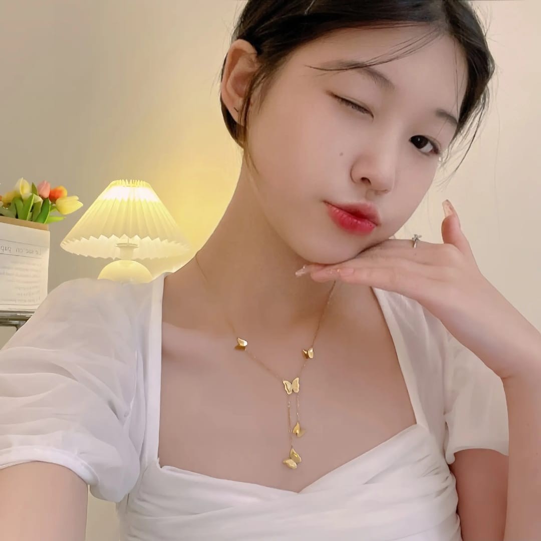 Woman wearing a delicate gold butterfly necklace by TITLIYA, featuring multiple butterfly charms on a thin chain.