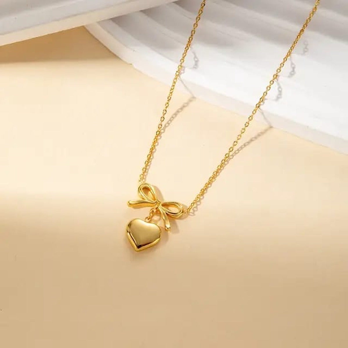 TITLIYA gold-tone necklace featuring a delicate heart and bow pendant on a fine chain for elegant daily wear.
