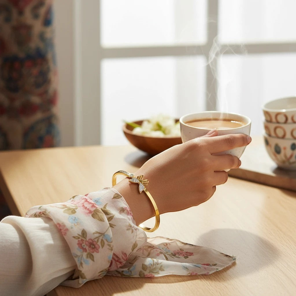 TITLIYA gold plated butterfly bracelet with crystal accents worn on a woman's wrist while holding a steaming cup.