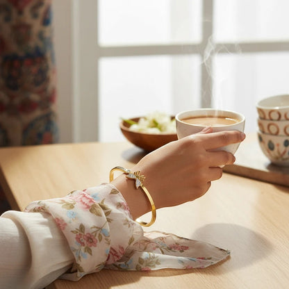 TITLIYA gold plated butterfly bracelet with crystal accents worn on a woman's wrist while holding a steaming cup.