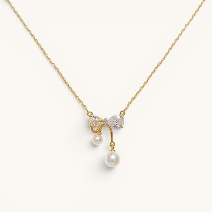 TITLIYA gold-plated necklace featuring a crystal bow pendant with two dangling white pearls on a delicate chain.