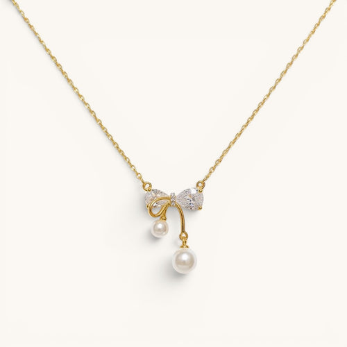 TITLIYA gold-plated necklace featuring a crystal bow pendant with two dangling white pearls on a delicate chain.