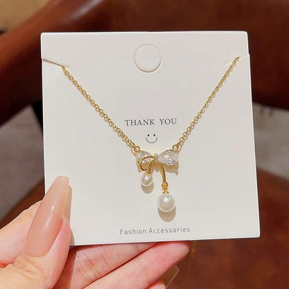 TITLIYA gold plated necklace featuring a crystal bow pendant with two dangling white pearls on a display card