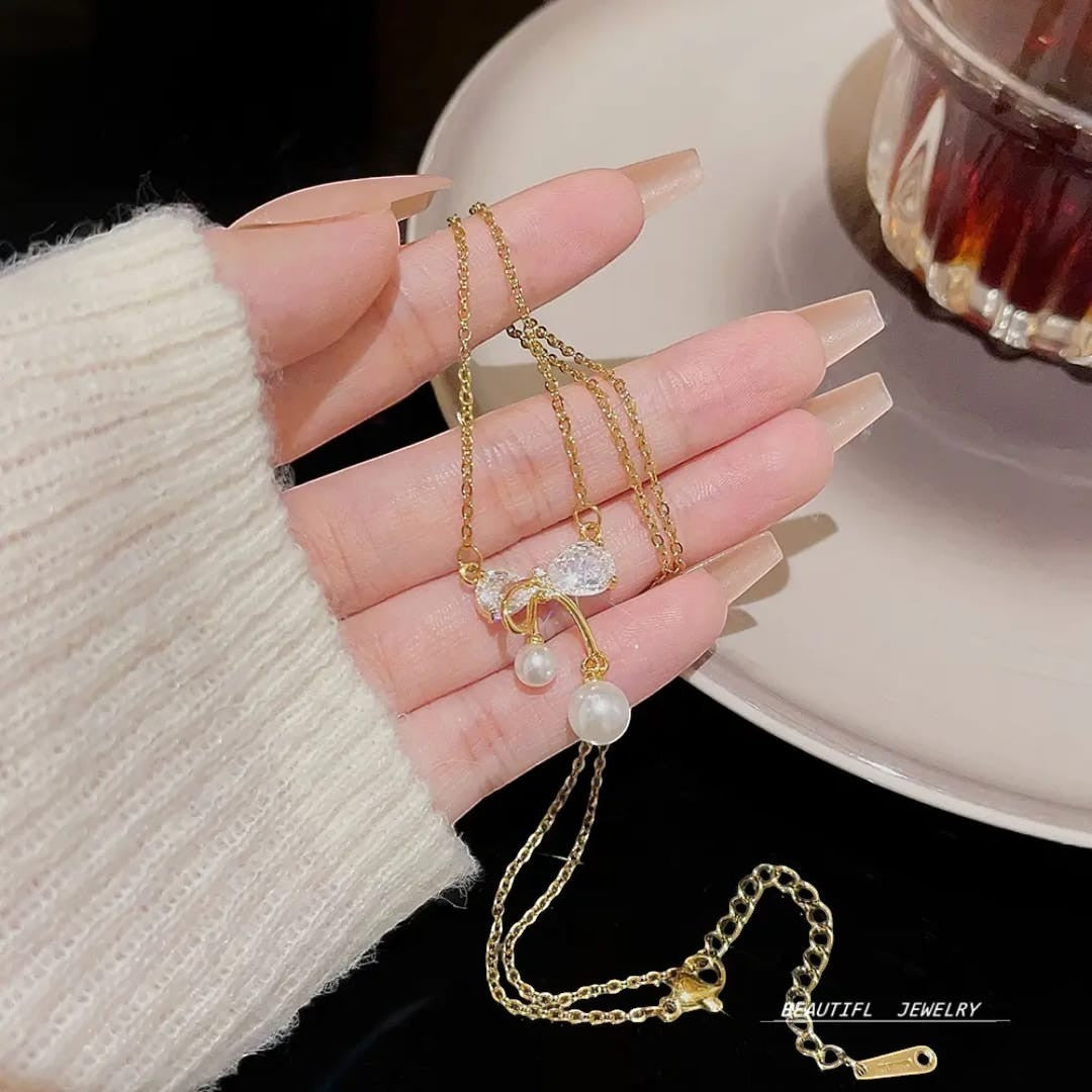 TITLIYA gold plated necklace featuring a delicate bow pendant with crystals and two dangling white pearls