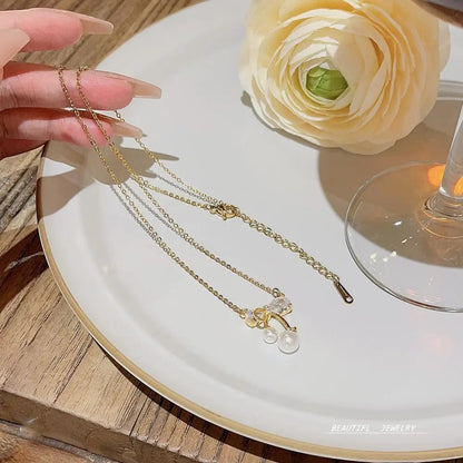 TITLIYA gold plated necklace featuring a delicate bow pendant with sparkling crystals and two small white pearls.