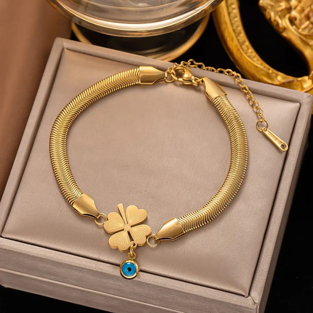 TITLIYA gold-tone snake chain bracelet featuring a heart-shaped four-leaf clover charm and a blue evil eye pendant.