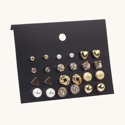 TITLIYA set of 12 gold-toned stud earrings featuring pearls, crystals, hearts, and geometric shapes on a black card.