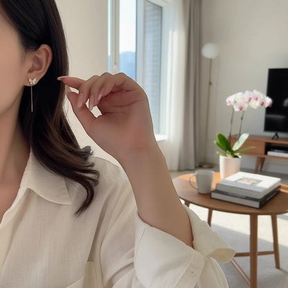 TITLIYA golden butterfly drop earrings with minimalist design worn by a woman in a bright, modern living room.