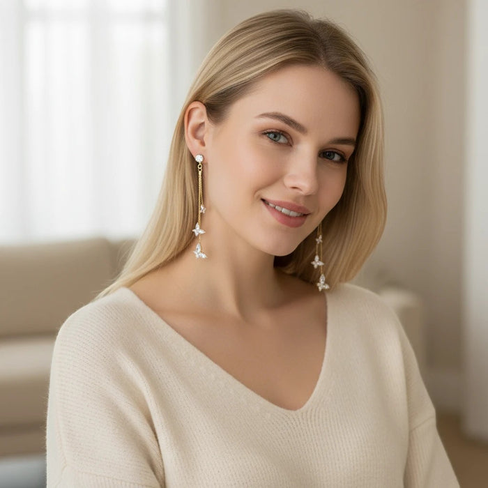 A blonde woman wearing TITLIYA golden butterfly drop earrings with delicate crystal tassels for a festive look.